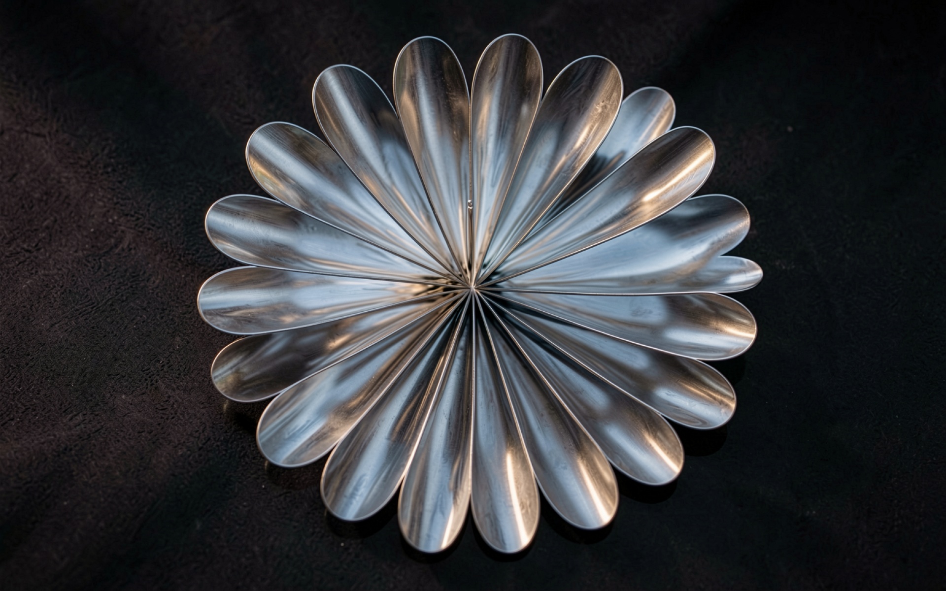 Композиция из стальных ложек на черном фоне