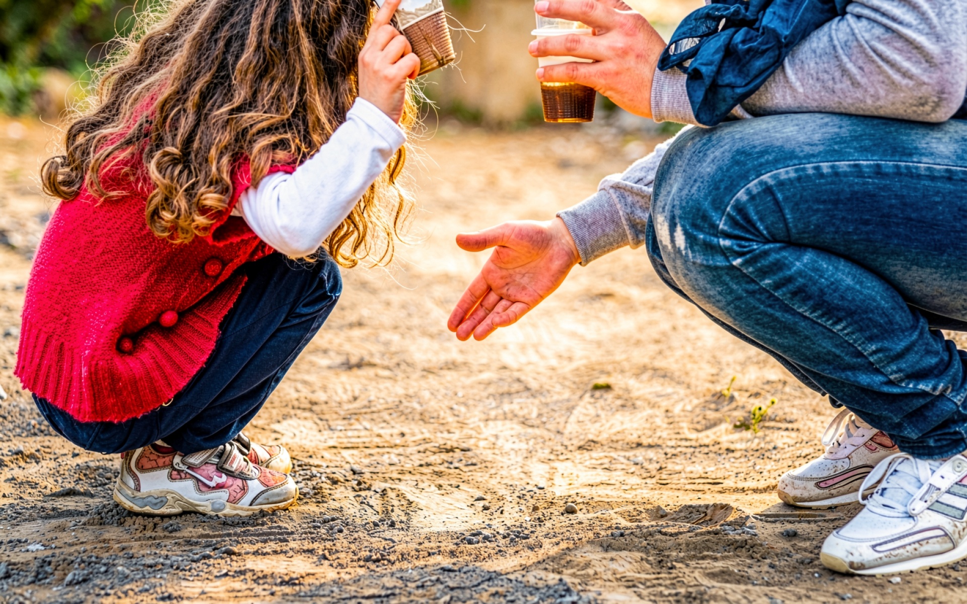 Ребенок и взрослый с напитками на песке