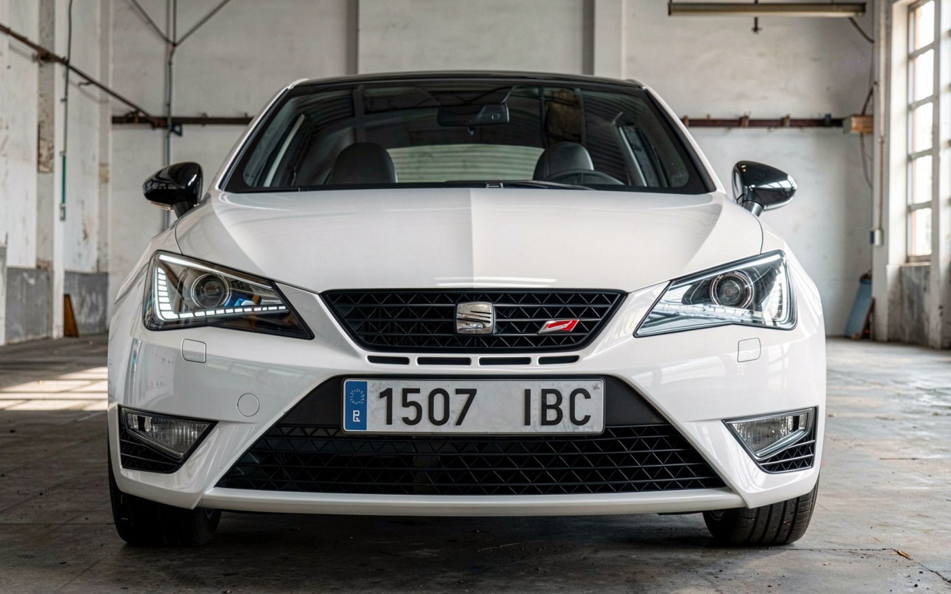 Белый автомобиль Seat Leon в индустриальном гараже