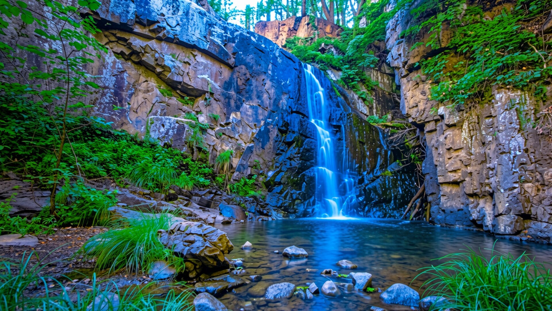 Водопад в темном скалистом ущелье с зеленью