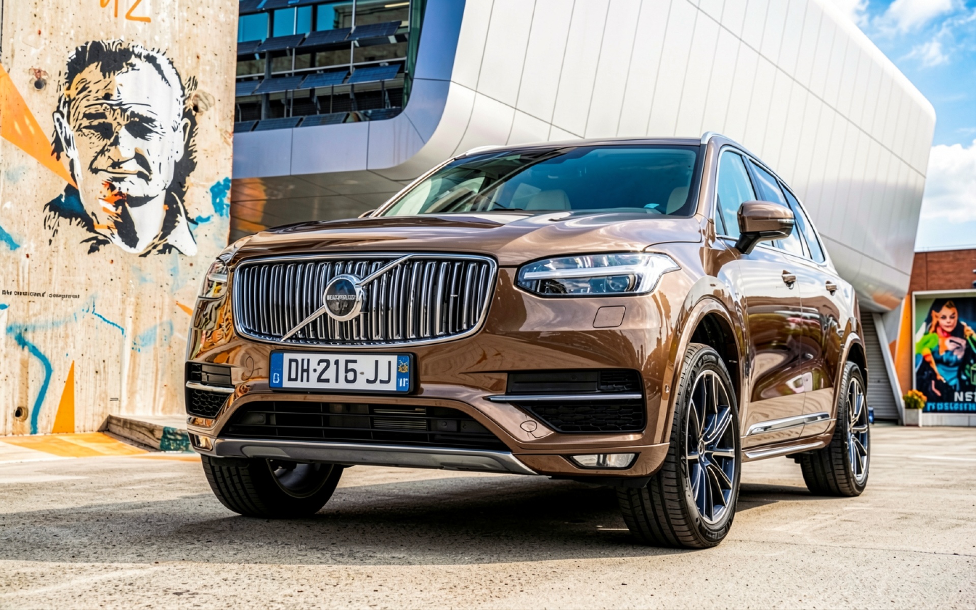 Коричневый кроссовер Volvo на фоне современного здания