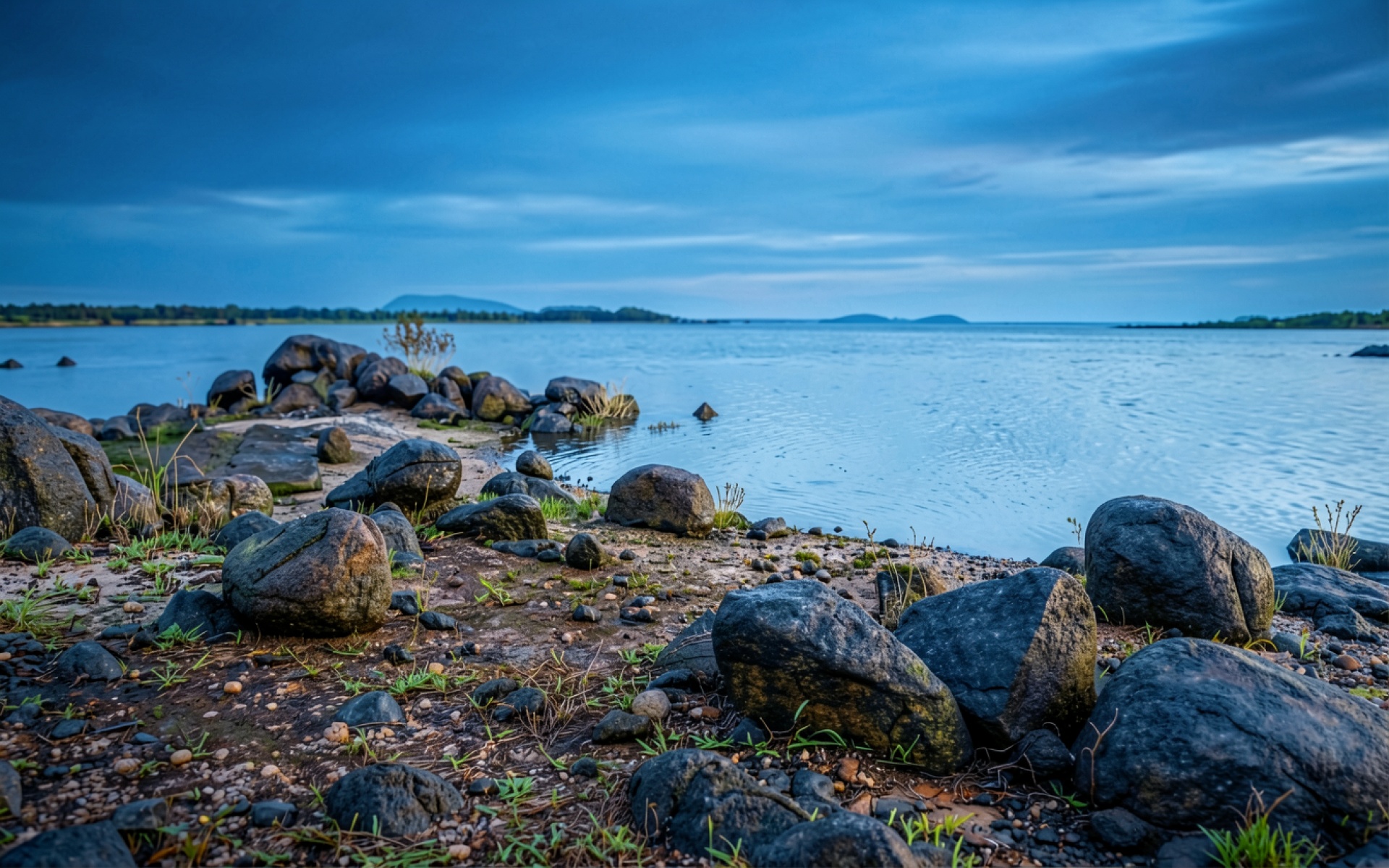 Серые камни на берегу синего озера