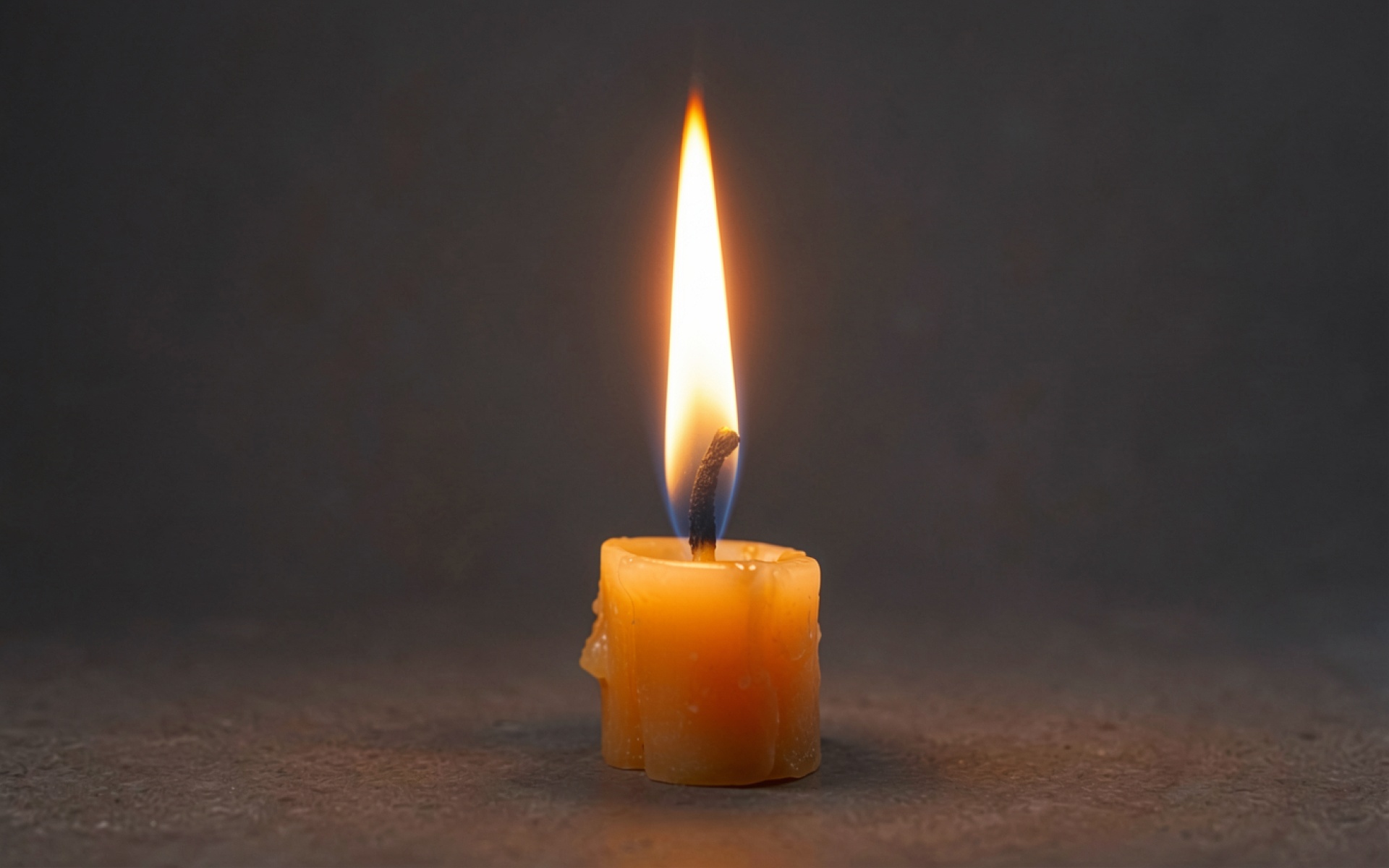 Горящая желтая свеча на темном фоне