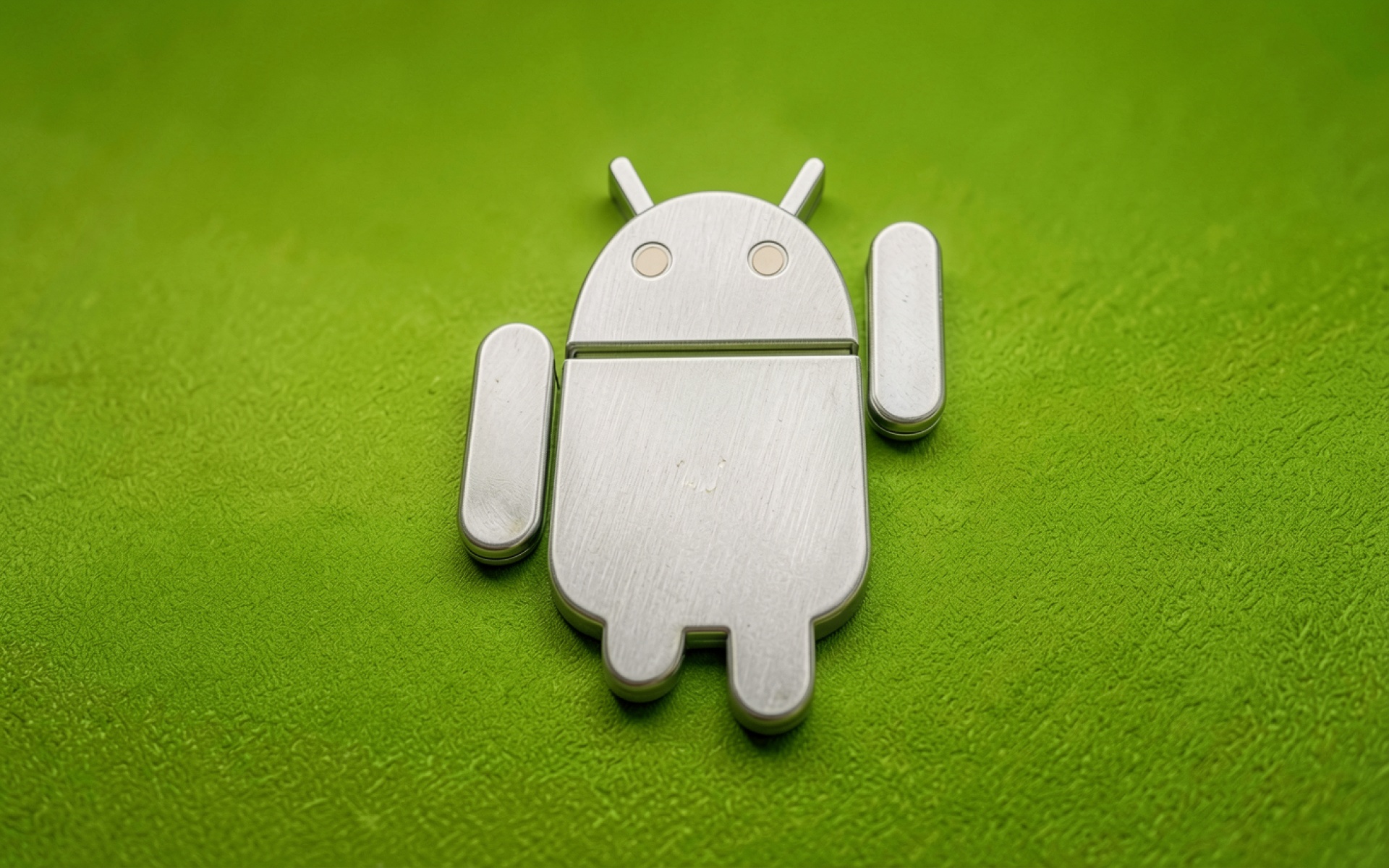 Металлическая фигурка Android на зеленом фоне