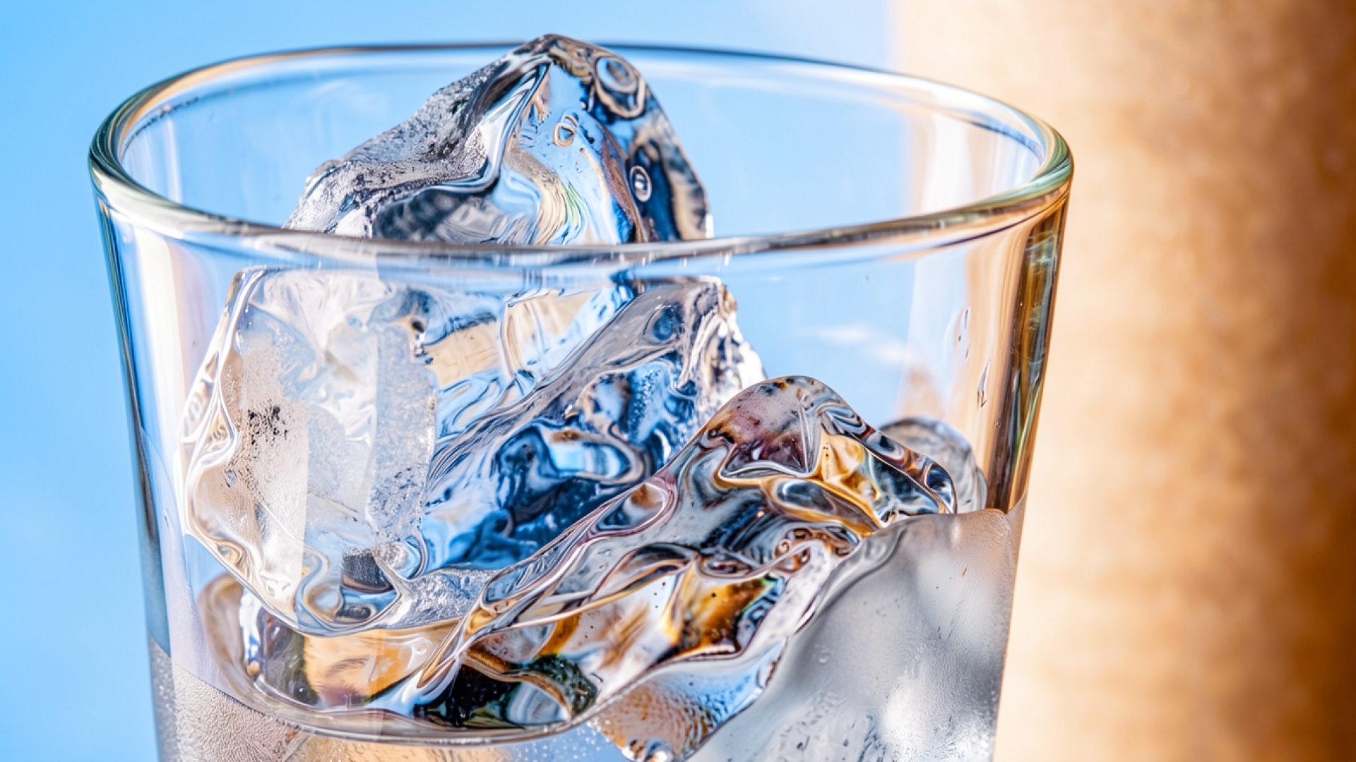 Кубики льда в стеклянном стакане синий фон