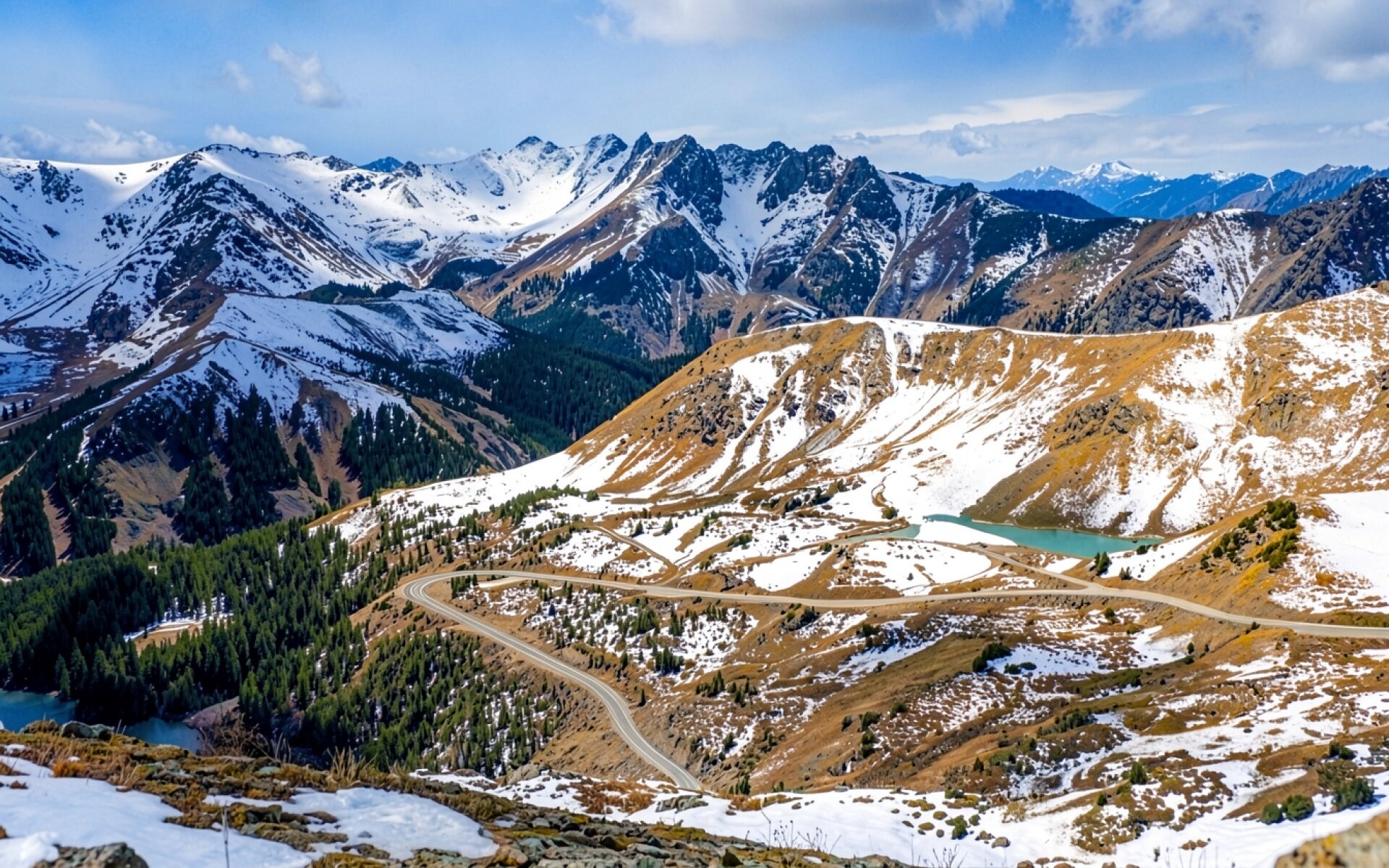 Заснеженные горы с извилистой дорогой и озером