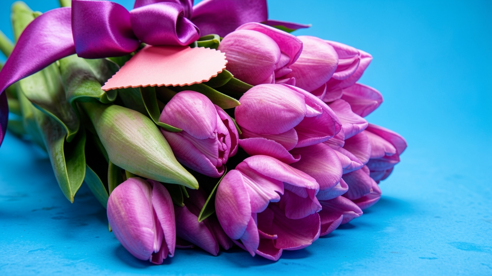 Букет розовых тюльпанов с лентой на голубом фоне