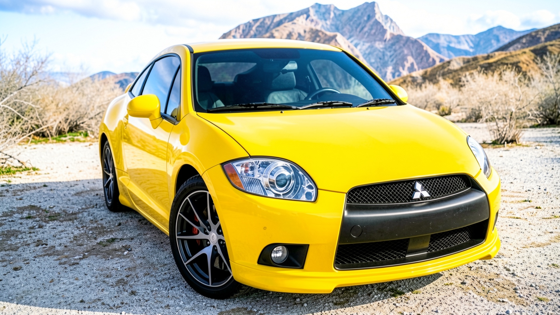 Желтый автомобиль Mitsubishi Eclipse на горном фоне