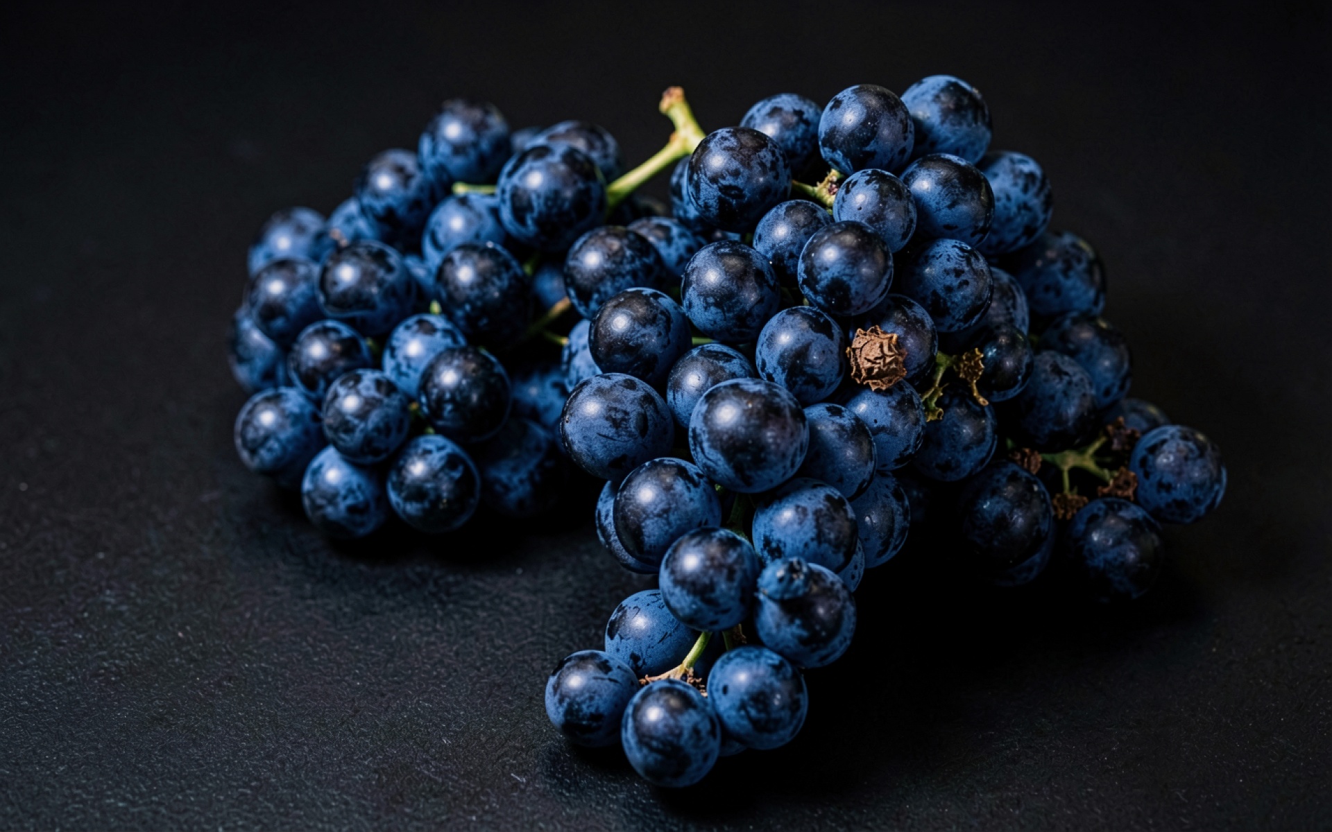 Синие гроздья винограда на черном фоне