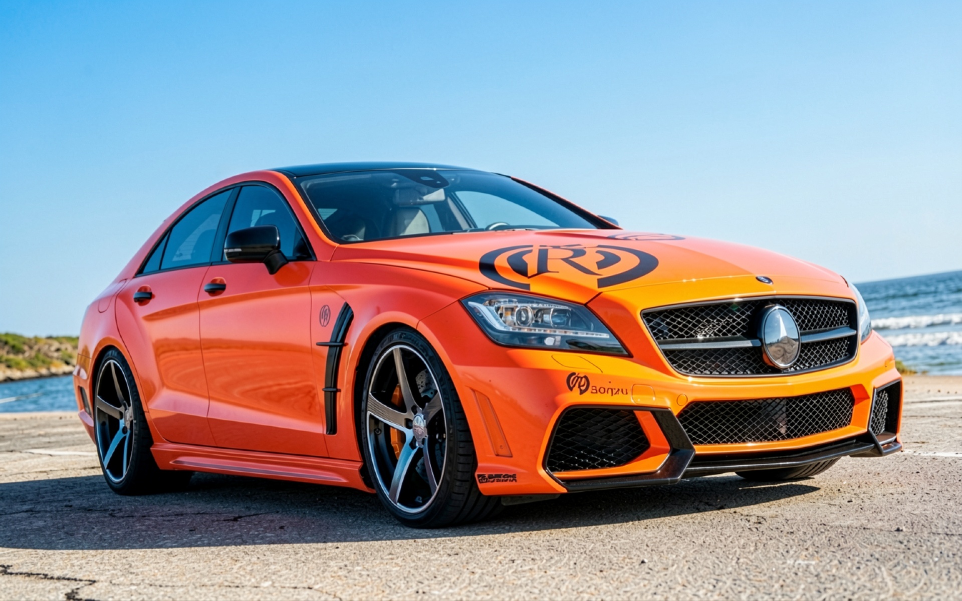 Оранжевый автомобиль Mercedes CLS на морском побережье