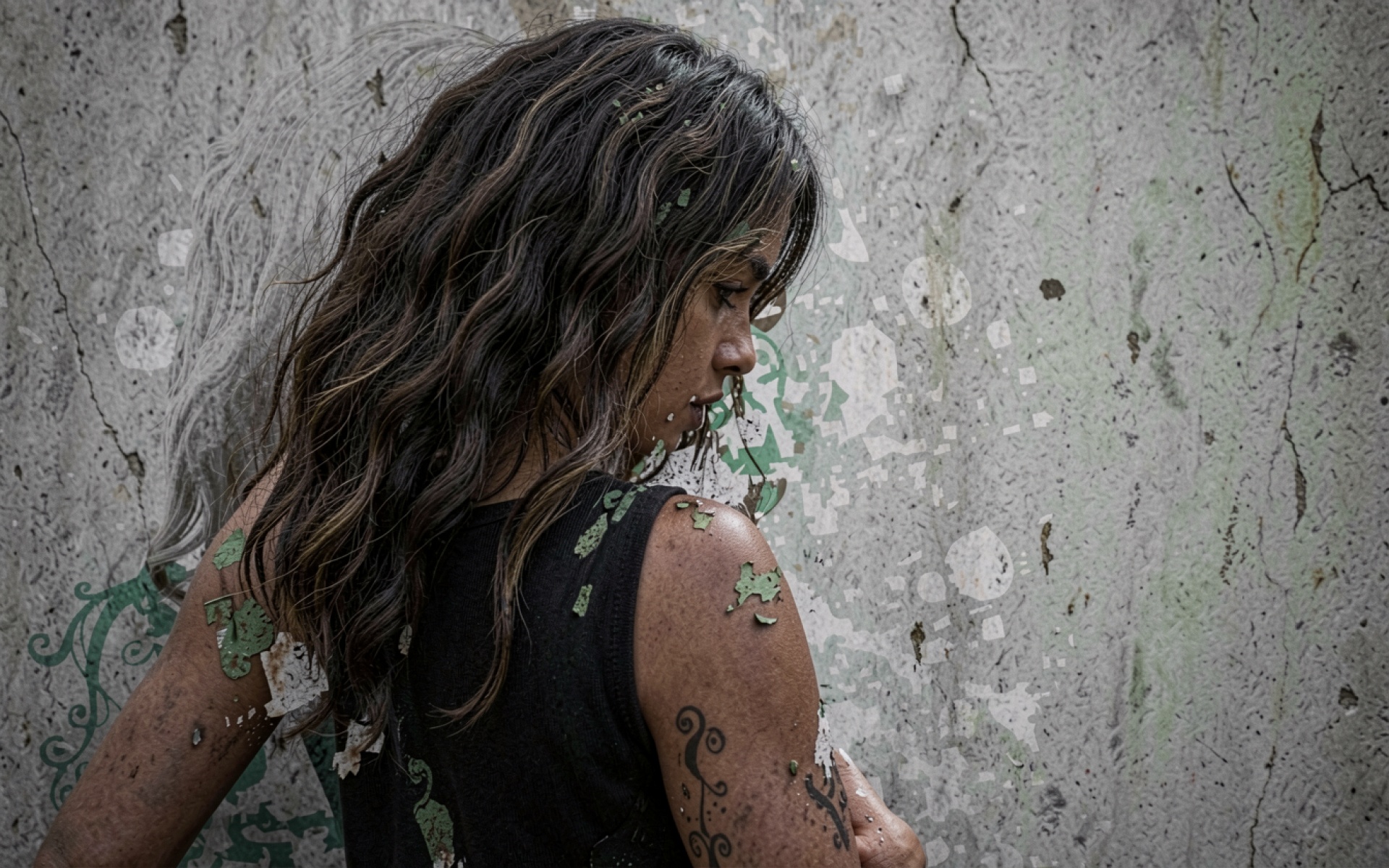 Девушка с татуировкой на фоне бетонной стены